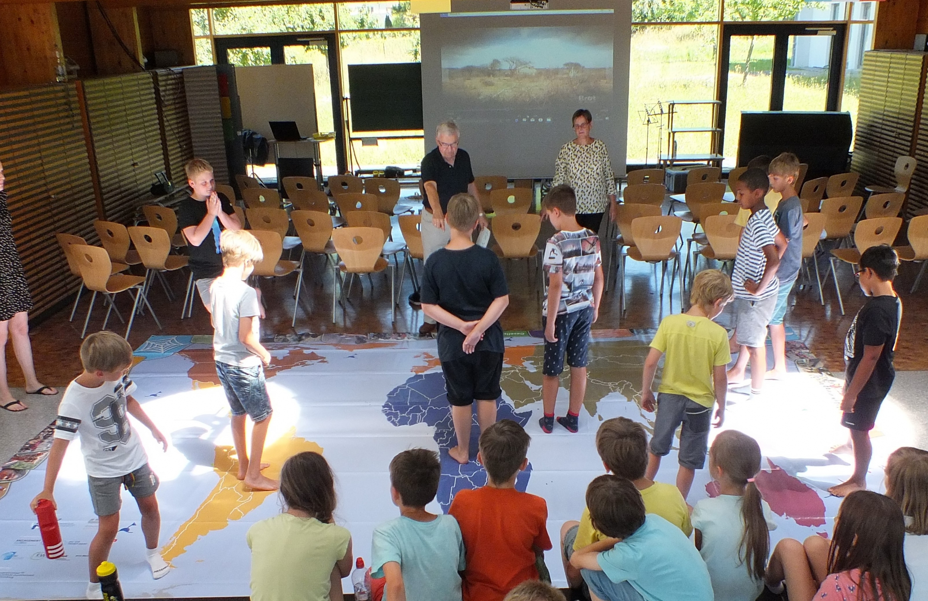 Schüler*innen im Gemeindesaal Hochdorf mit der Weltspielplane
